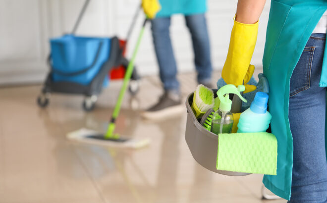 Female janitor with cleaning supplies in kitchen